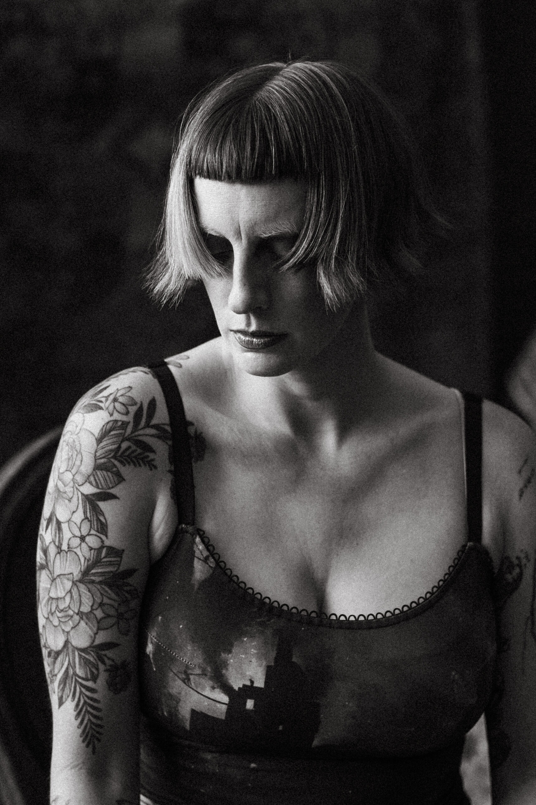 Moody black and white portrait from the chest up. The hair falling into face looking down.